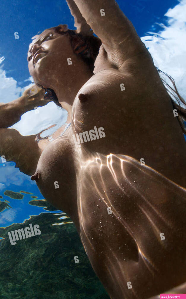 Underwater view of young Asian nude woman partially submerged sitting with hands behind head Stock Photo